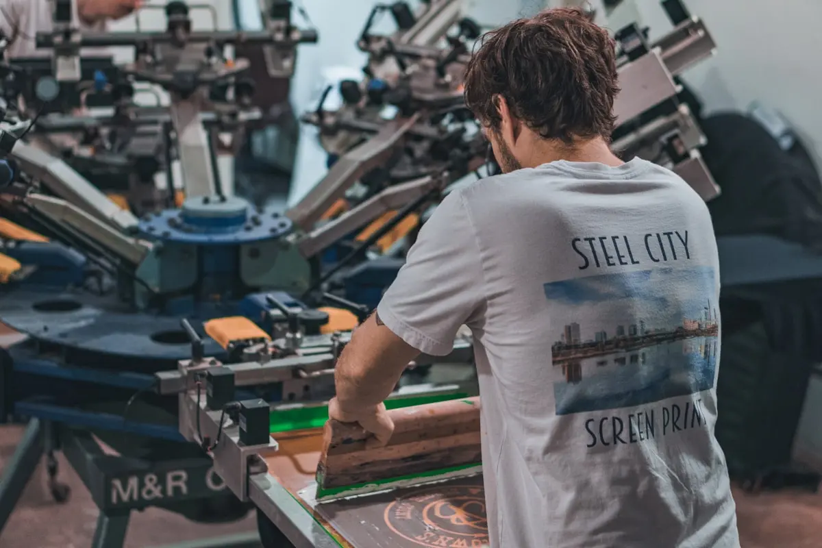 Processo de silk screen (serigrafia) sendo aplicado em camiseta para uniforme de equipe
