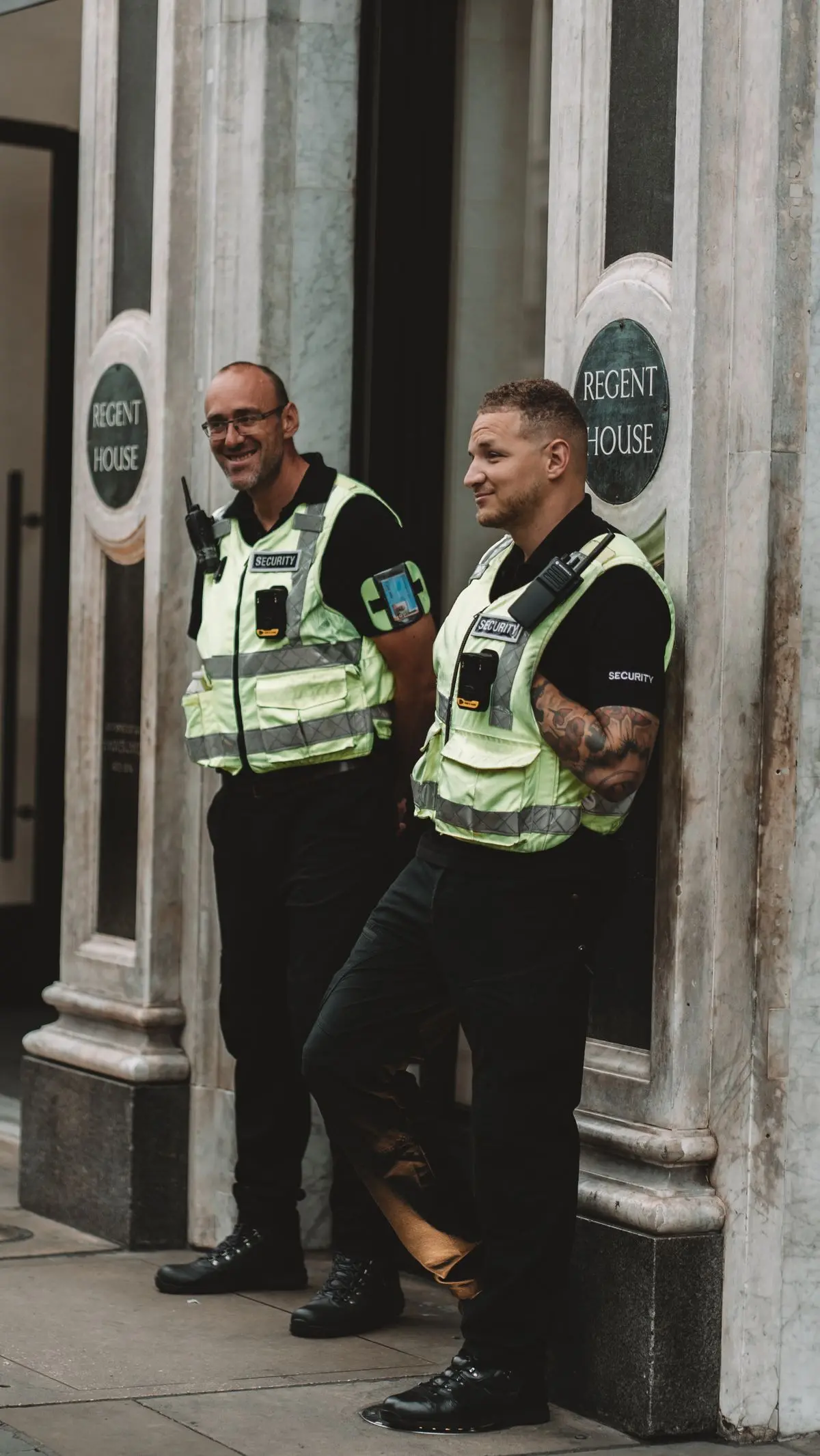 Dois seguranças uniformizados de prontidão na entrada de um edifício