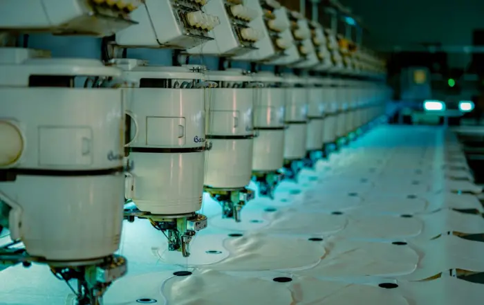 Linha de máquinas de costura industriais em fábrica de confecção produzindo uniformes