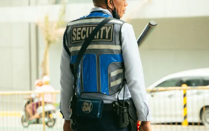 Vigilante com uniforme de segurança patrimonial em via pública, mantendo a vigilância