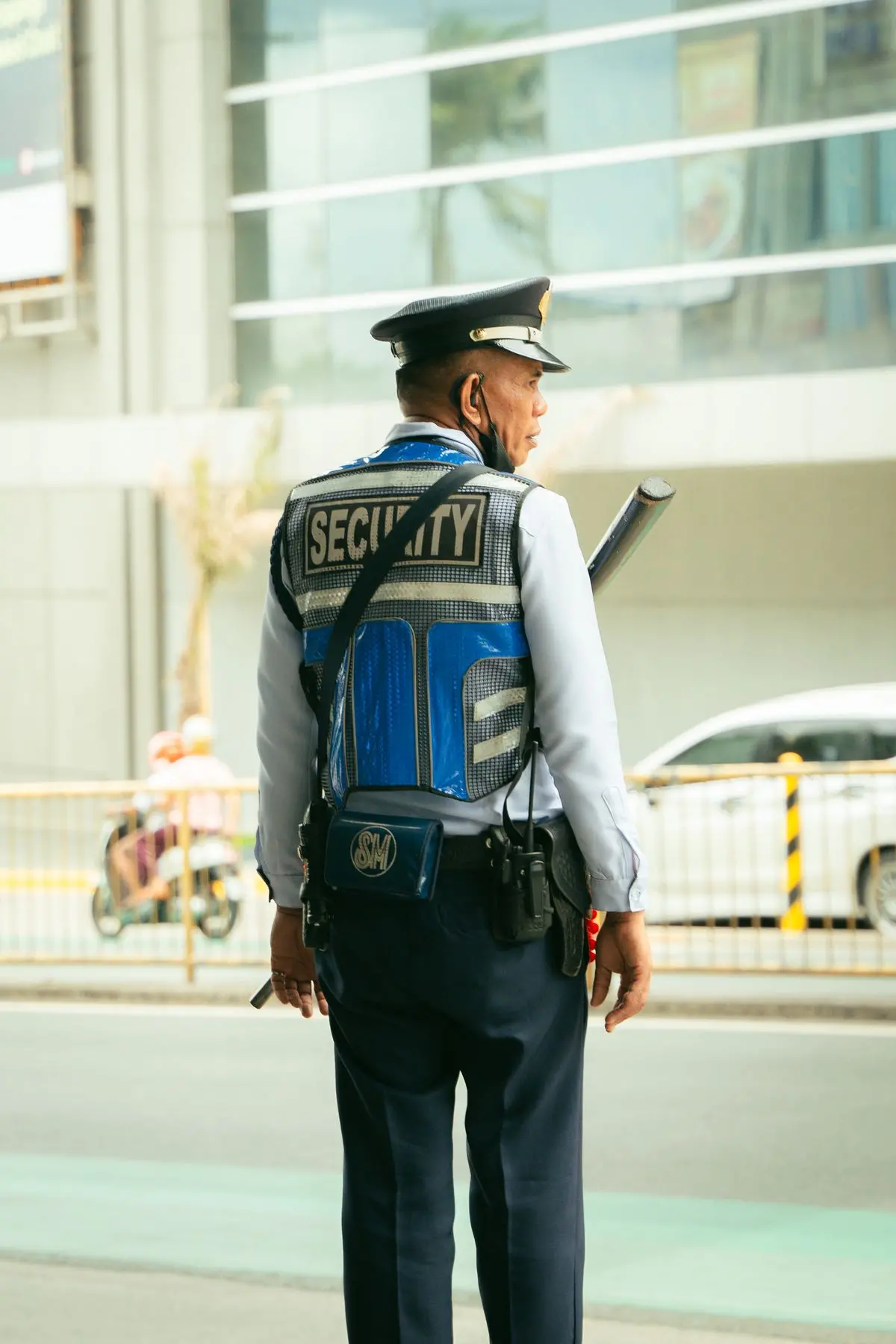 Vigilante com uniforme de segurança patrimonial em via pública, mantendo a vigilância